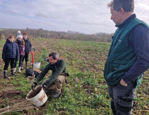 Olivier Tassel (au premier plan) écoute les consignes de plantation que Benoit Caumont, spécialiste en agroforesterie, partage avec les enfants. 